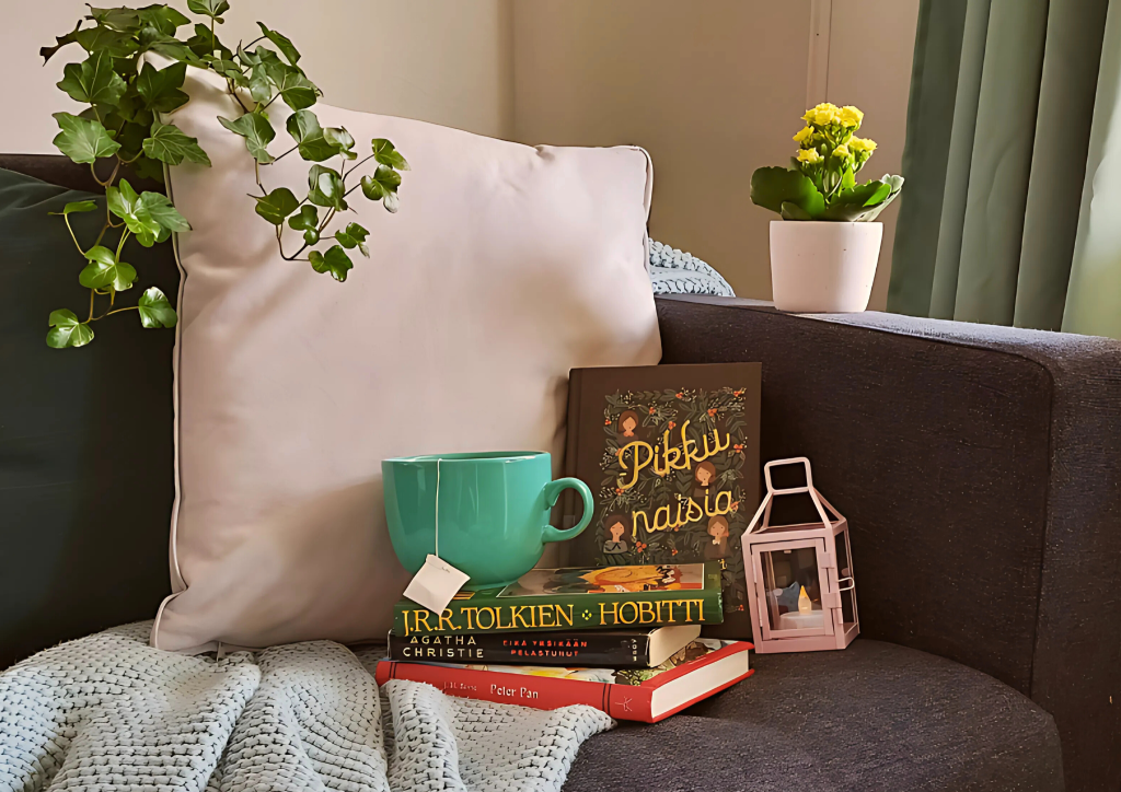 Sohvalla klassikkokirjoja, teekuppi, tyynyjä ja lyhty