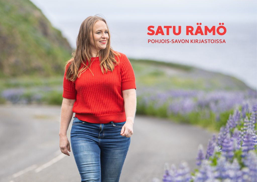 Hymyilevä Satu Rämö kävelemässä islantilaista tietä pitkin punaisessa paidaassa ja farkuissa.