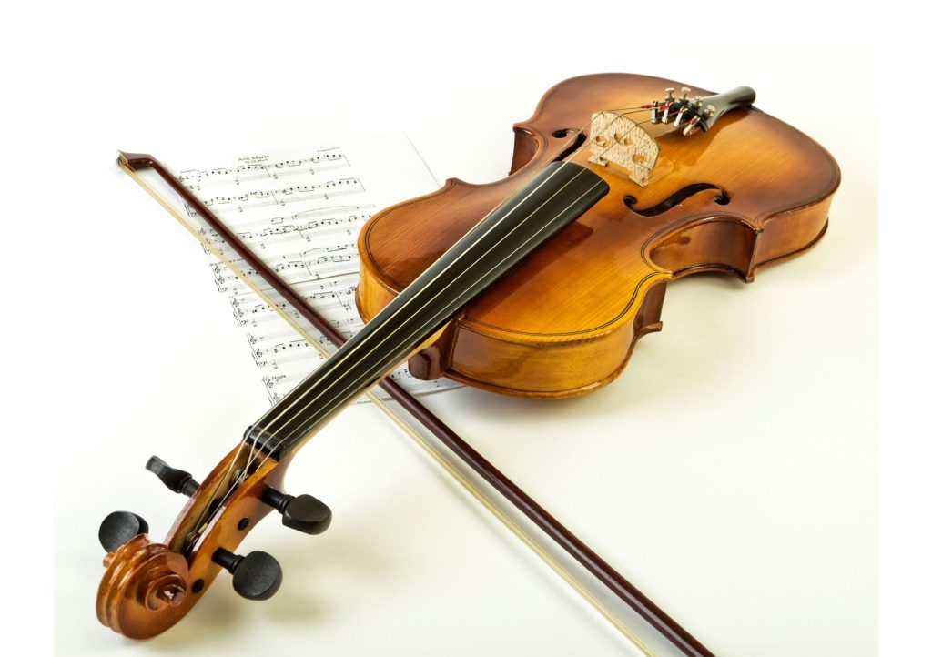 Vaalealla pohjalla viulu ja jousi nuottivihkon päällä